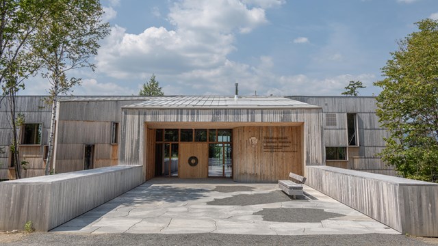 A photo of a wooden building with double doors and a blue sky in the background.