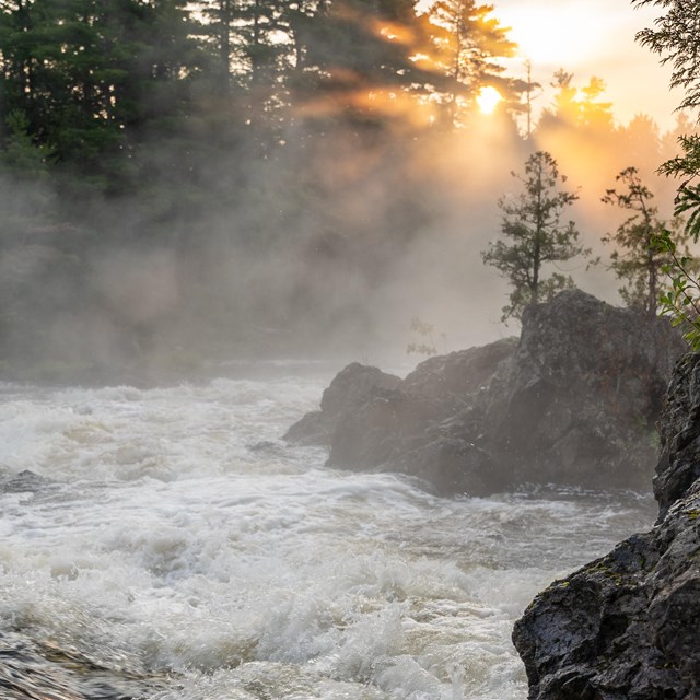A river with a very strong current at sunrise, mist rising in the early morning sun. 