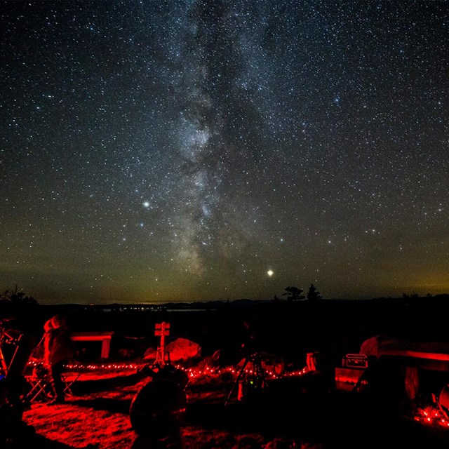 Visitors participating at a night sky programing event at the Katahdin Overlook with stars above.