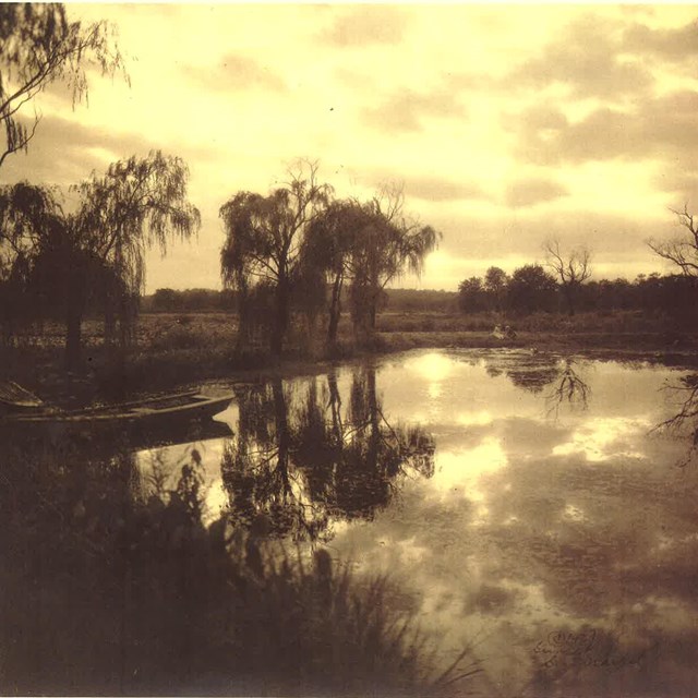 An old brown sepia photo of lakes and trees.