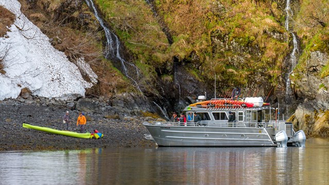 A boat drops off kayakers on shore