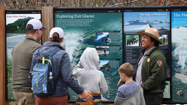 A park ranger speaks to visitors at a map board.