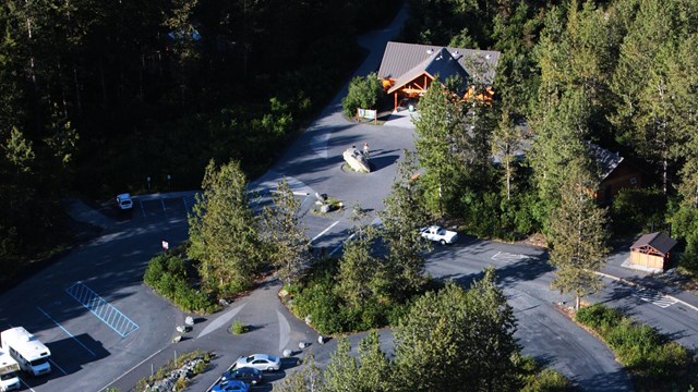 An aerial view of parking lot and visitor center amongst forest
