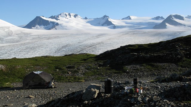 Gear and tent with icefield in the distance