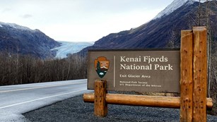 a picture of the park sign along the road to Exit Glacier with the glacier in the distance