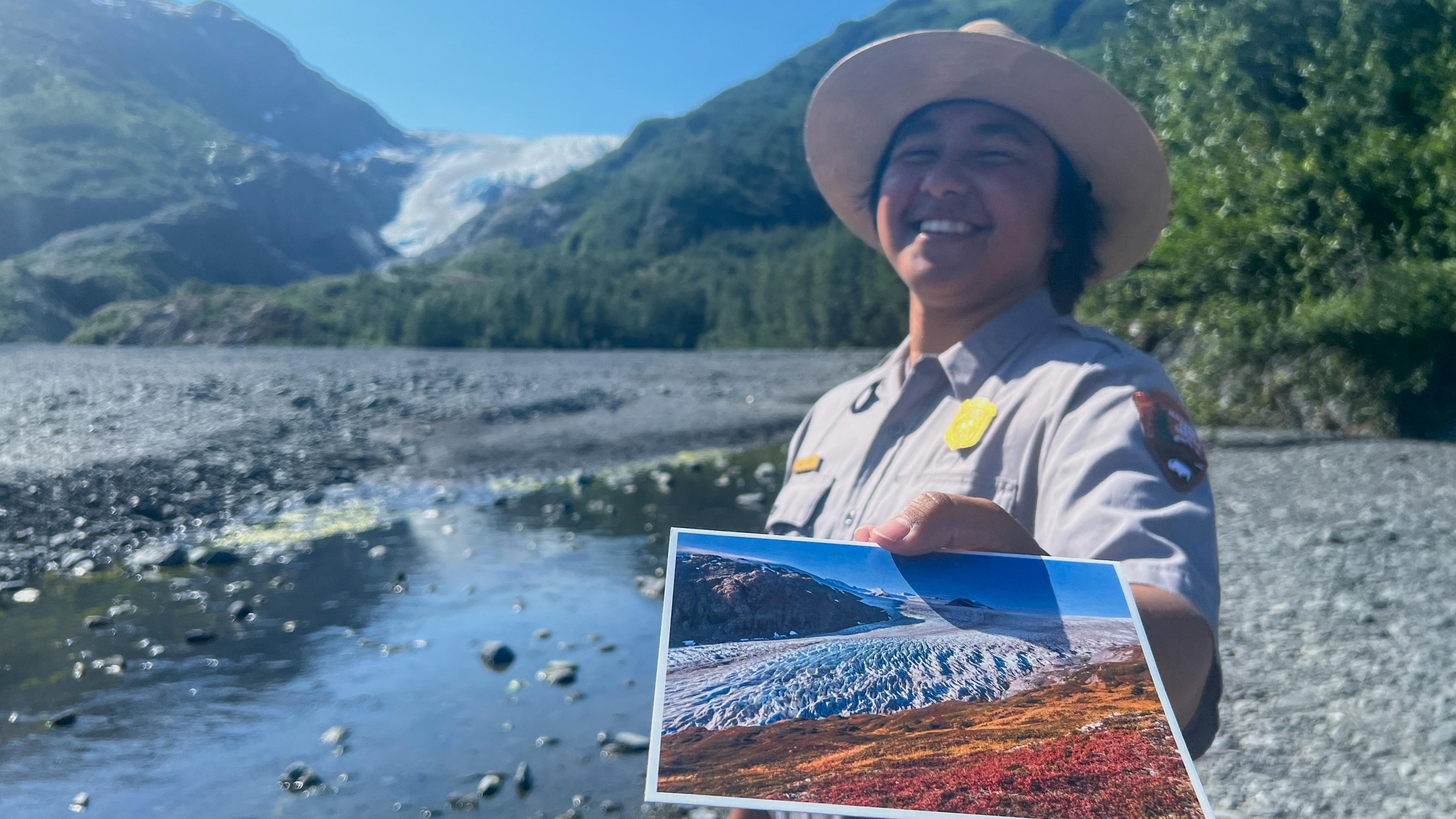 A ranger holds a postcard of a glacier