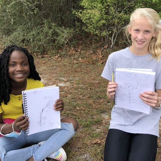 Two young girls holding nature journals.