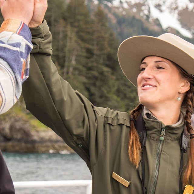 A park ranger high fives a visitor. 