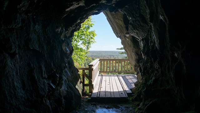 Looking outside of a mine adit onto a deck overlooking the forest.
