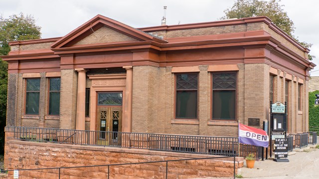 Exterior image of a historic Carnegie Library with two pillars.