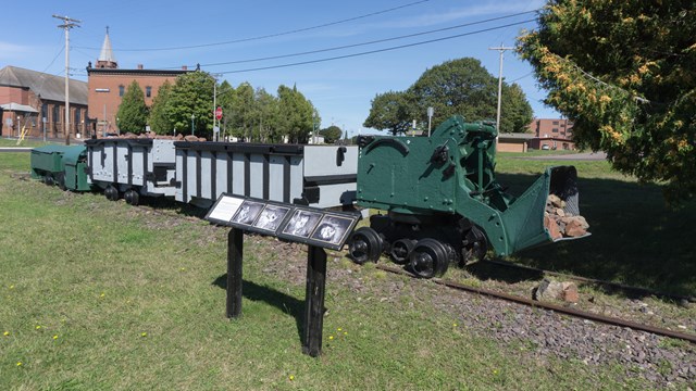 Historic cart with rocks on it on a track outside.