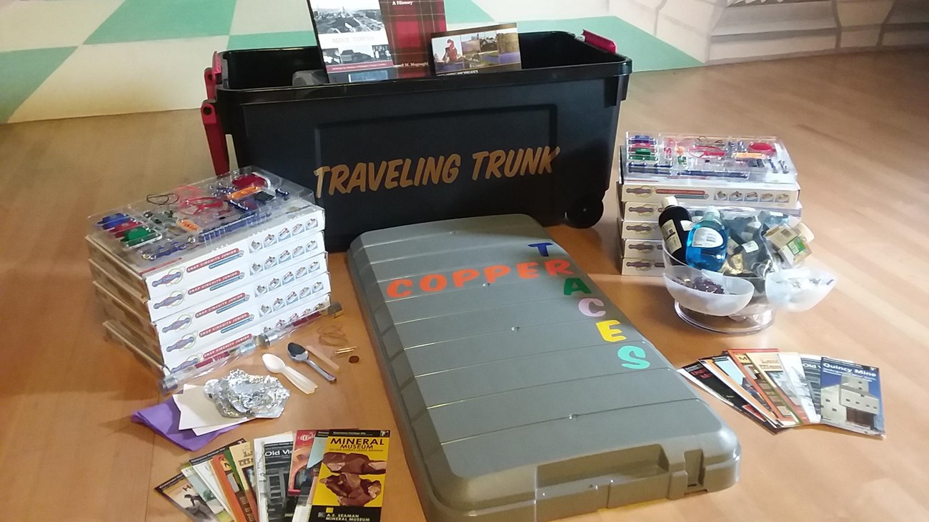 An assortment of items like snap circuit sets and brochures surround a trunk.