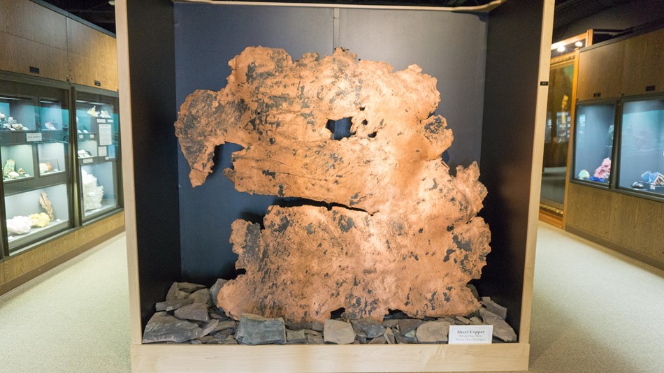 A large piece of copper is displayed inside of a museum.