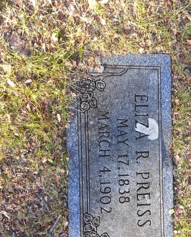 A flat grave marker with name, birth, and death information.