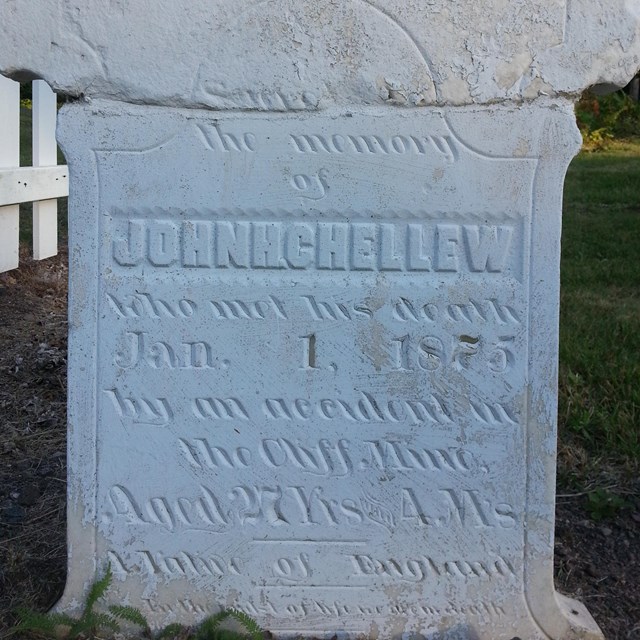 A close-up of the bottom of a white grave marker.