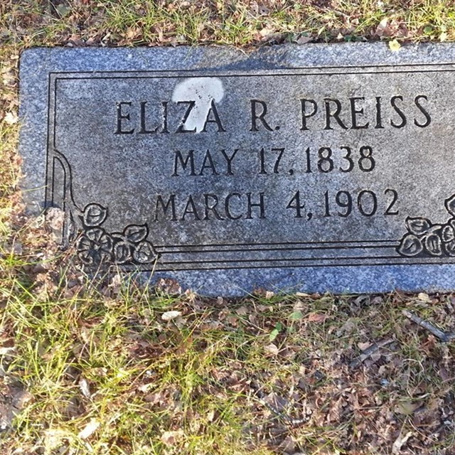 A flat grave marker with name, birth, and death information.