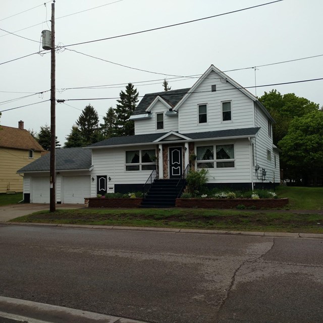 A two-story house with a connected two-car garage sit in front of a street.