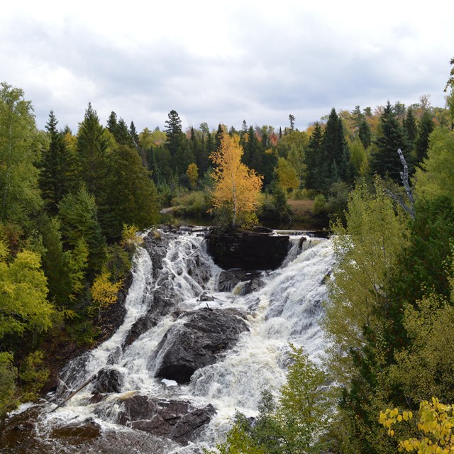 A background building has a waterfall in the foreground.