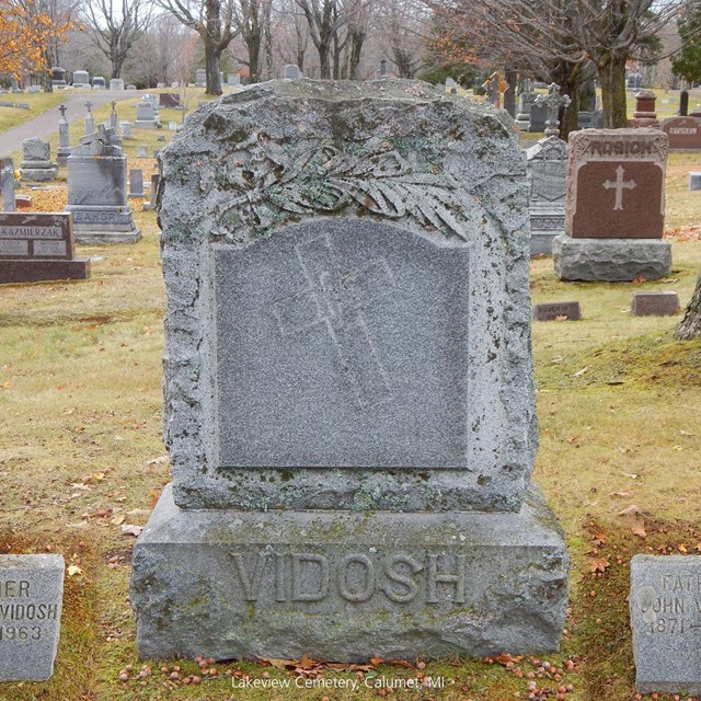 A tall grave marker is flanked by two smaller markers.