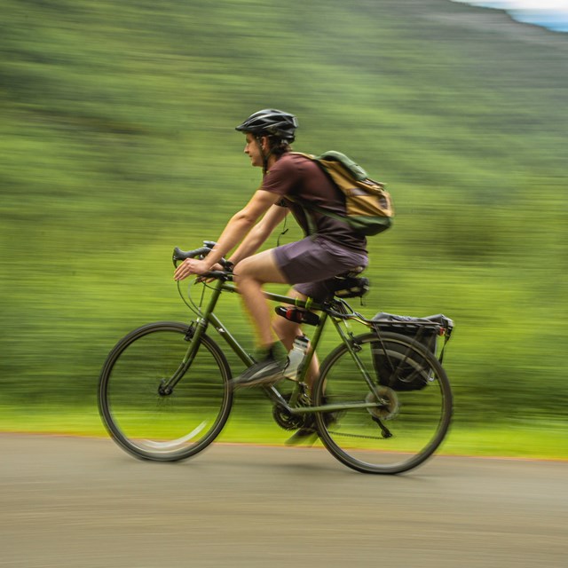 a man wearing a helmet rides a bicycle on a path