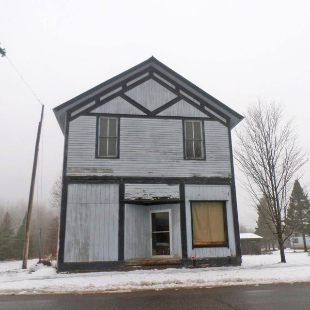 A dilapidated wood-sided, two-story building.