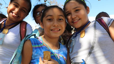 Four girls look proud wearing their Junior Ranger badge.
