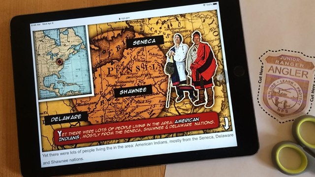 An iPad displays a comic book style online junior ranger activity with printed badge and scissors.