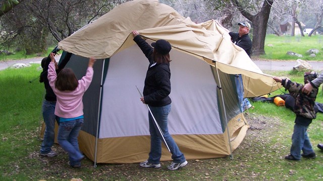 Parents and kids put a roof over their tent.