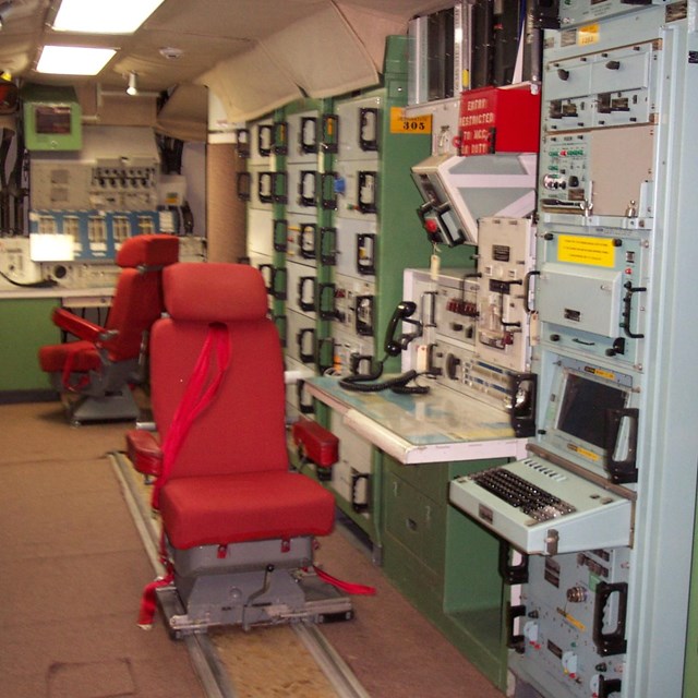 Red seats centered amid avocado panels of buttons and switches used to launch missiles
