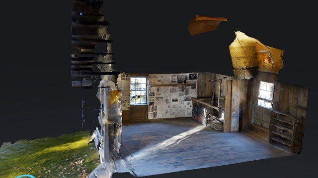 Side view through the walls of a small, one room cabin, with some grass out front