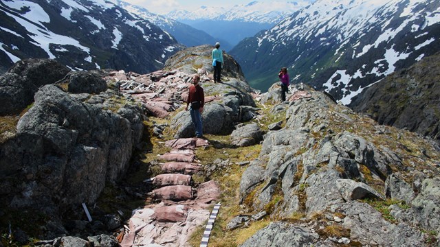 People stand amid canvas bundles on a mountain pass