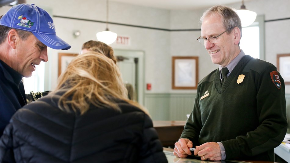 A ranger behind a desk faces two people