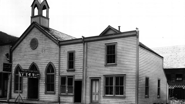 Black and white photo of church with sign reading "Presbyterian Church Y.M.C.A Free Reading Room"