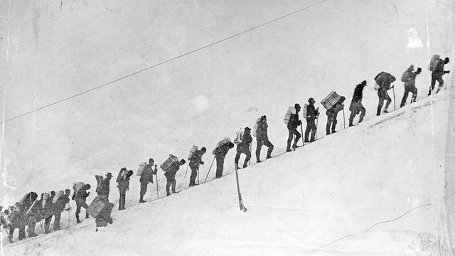 Black and white photo of a line of stampeders in the snow
