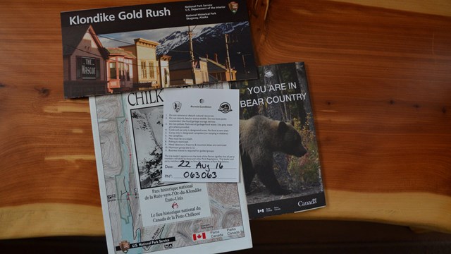 Brochures and a hiking permit on a wood surface