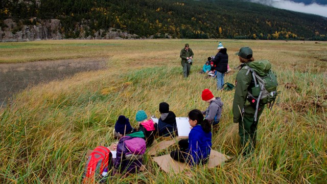 Kids and rangers sitting in a natural area