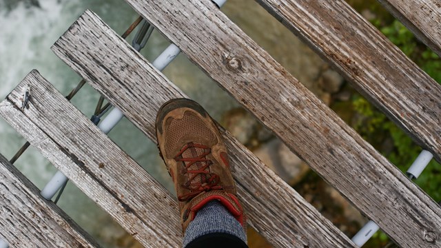 Hiking boot on bridge with river below