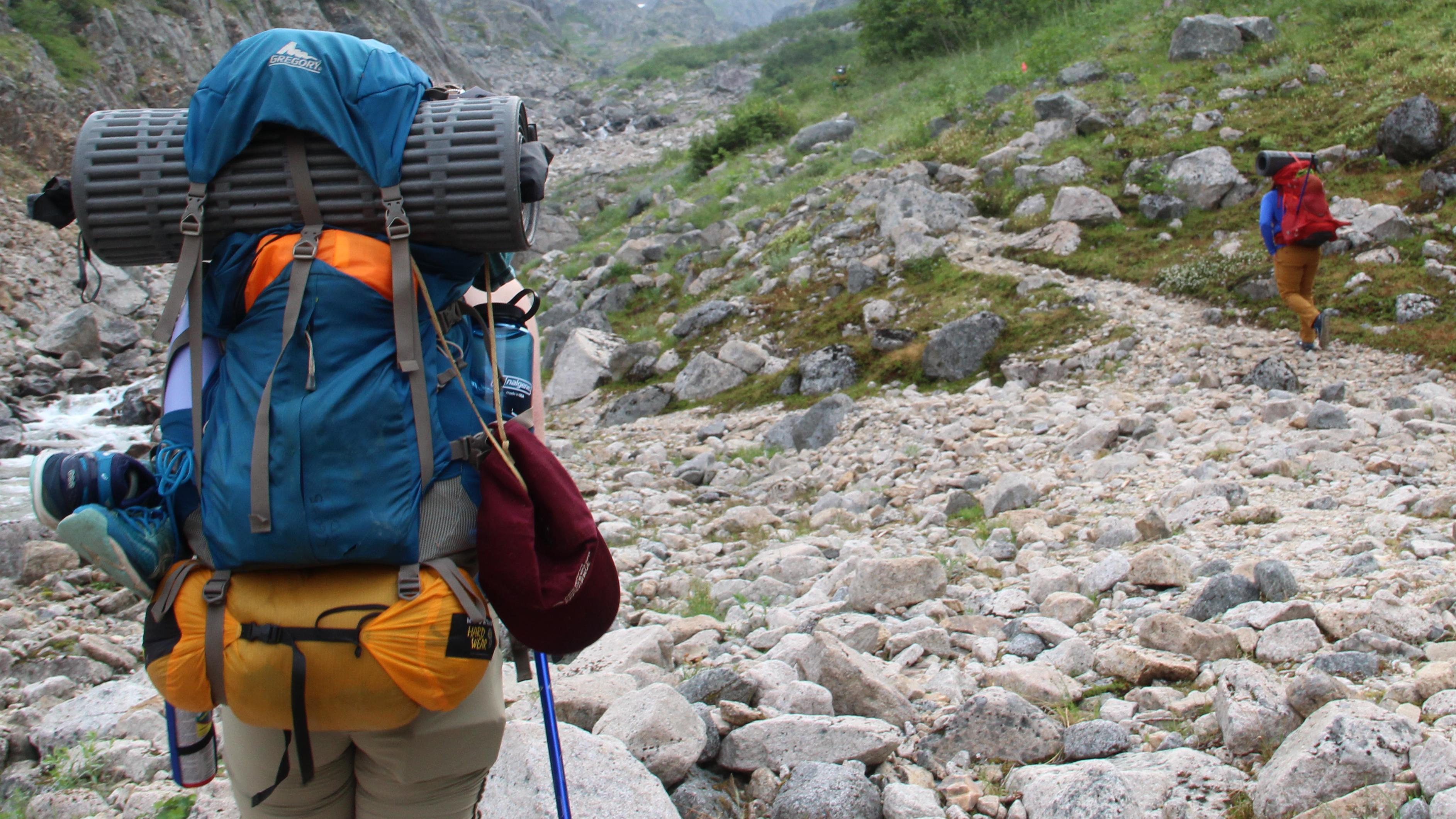 A backpacker hikes on rocky terrain