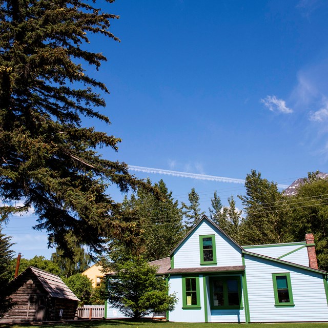 a bright blue building and small log cabin under a blue sky
