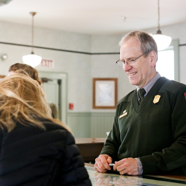 A ranger behind a desk faces two people