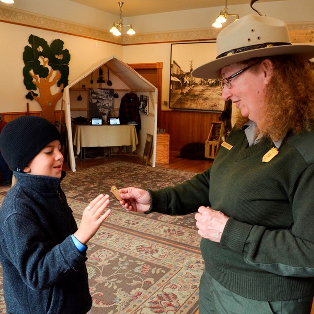 A ranger hands a badge to a boy