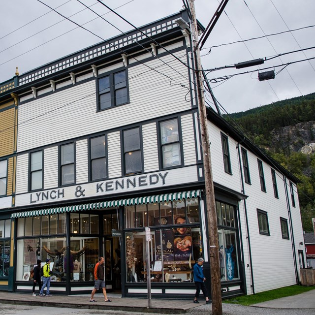 Two story white building with a false front and green trim. Sign reads Lynch & Kennedy