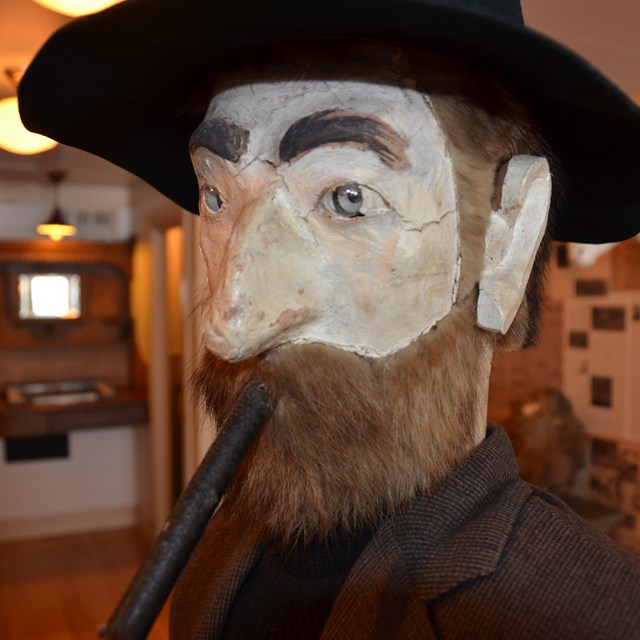 Close up of manikin head with beard, cigar, and black hat