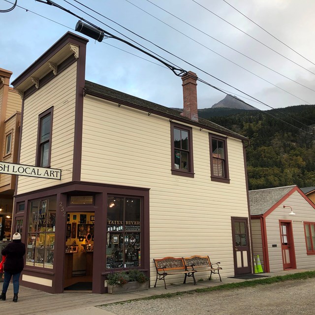 A small two story white building with small gray building behind it