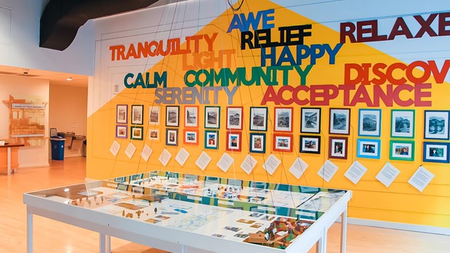 Exhibit with words on wall, picture frames, and tables located in the middle of the room