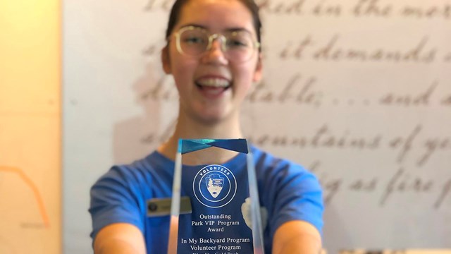 Person smiling, holding an award to camera