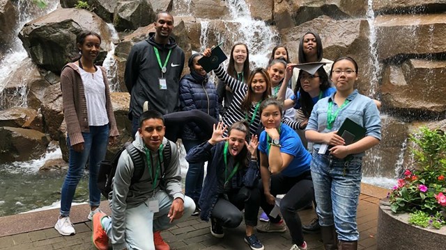 Group of people posing for the camera in front of a waterfall