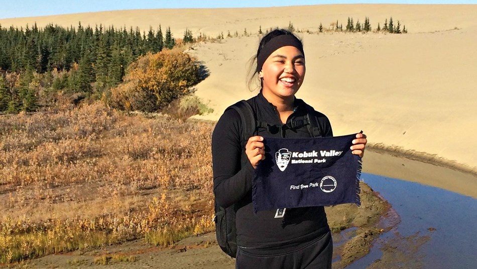 girl holding towel in from of sand dunes and a river
