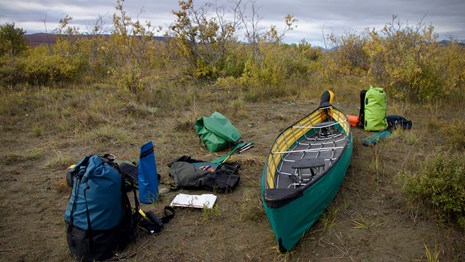 Canoe and outdoor gear sitting along the river bank.