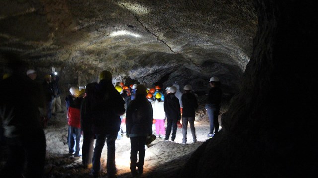 A cave illuminated by lights of a school group.